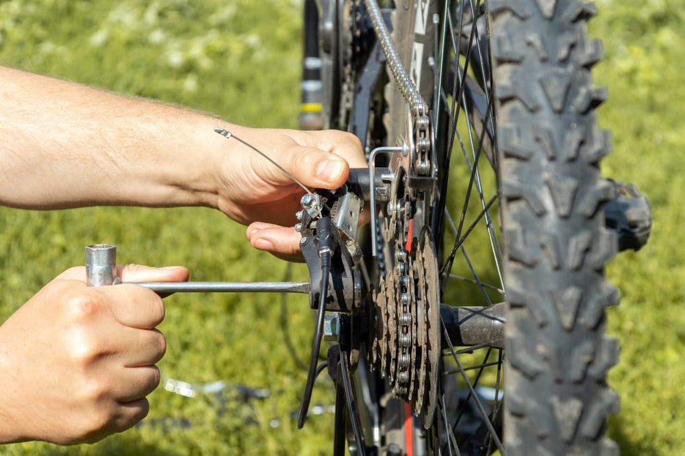 A mechanic repairs a bicycle chain on the street with a special